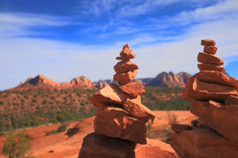 Two stacked stone cairns in the red rock desert of Sedona under a blue sky